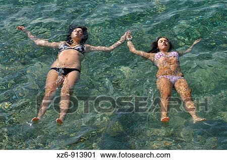 two girls floating in the sea, hand in hand View Large Photo Image Stock Image - two girls floating in the sea, hand in hand. Fotosearch