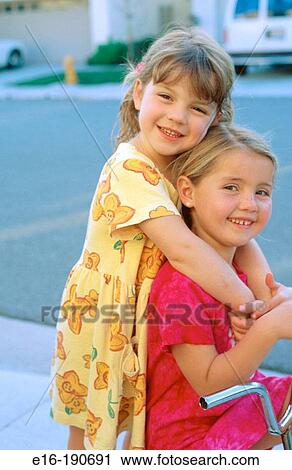Two girls hugging on bike View Large Photo Image Stock Image - Two girls hugging on bike. Fotosearch