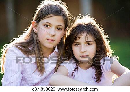 Two girls looking at the camera serious View Large Photo Image Stock Photograph - Two girls looking at the camera serious. Fotosearch