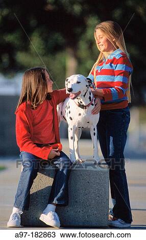 Stock Image - Two girls outside with their dog. Fotosearch