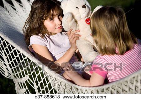 Two girls playing with a teddy bear View Large Photo Image Stock Photo - Two girls playing with a teddy bear. Fotosearch