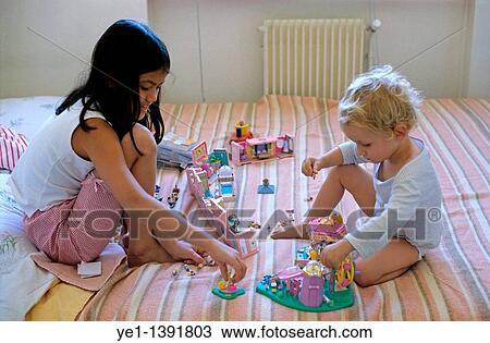 Two girls playing with toys on a bed, France View Large Photo Image Stock Image - Two girls playing with toys on a bed, France. Fotosearch
