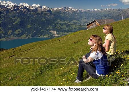 two girls relaxing, enjoying summer and nature in the sunshine, Swiss Alps, Niederhorn, view for Lake Thun, Bern canton, Switzerland View Large Photo Image Picture - two girls relaxing, enjoying summer and nature in the sunshine, Swiss Alps, Niederhorn, view for Lake Thun, Bern canton, Switzerland. Fotosearch