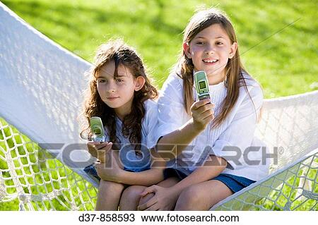 Two girls sending messages with their mobile phone View Large Photo Image Stock Image - Two girls sending messages with their mobile phone. Fotosearch
