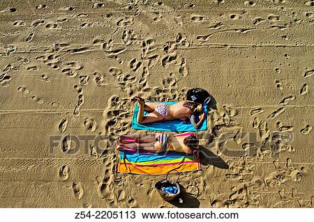 Stock Image - Two girls, siesta on beach, Salinas, Asturias; Spain.. Fotosearch