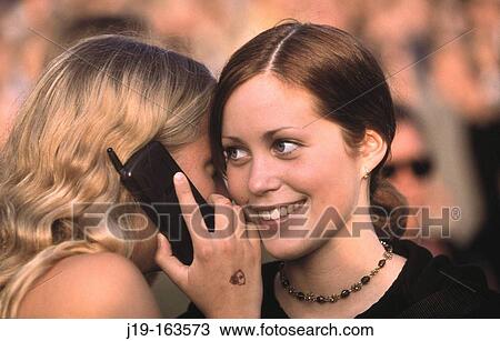 Stock Image - Two girls talking on phone. Fotosearch