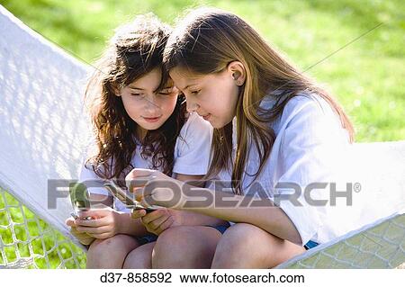 Two girls using their mobile phone View Large Photo Image Stock Image - Two girls using their mobile phone. Fotosearch
