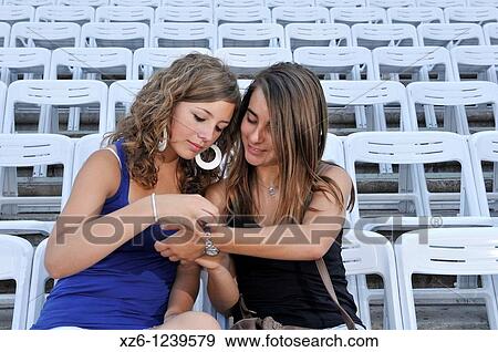 Two girls waiting for the concert in the terraces View Large Photo Image Stock Photo - Two girls waiting for the concert in the terraces. Fotosearch