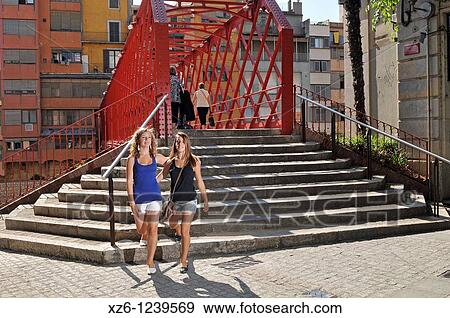 Stock Photo - Two girls walking front the Eiffel bridge in Girona, Catalonia, Spain, Europe. Fotosearch