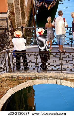 Two gondoliers on a bridge waiting for tourists, with a gondola, Venice, Italy. View Large Photo Image Stock Photo - Two gondoliers on a bridge waiting for tourists, with a gondola, Venice, Italy.. Fotosearch