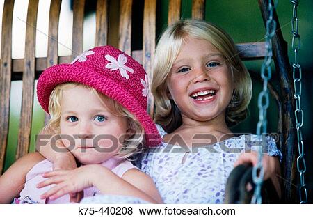 Stock Photo - two happy sisters on a porch swing. Fotosearch