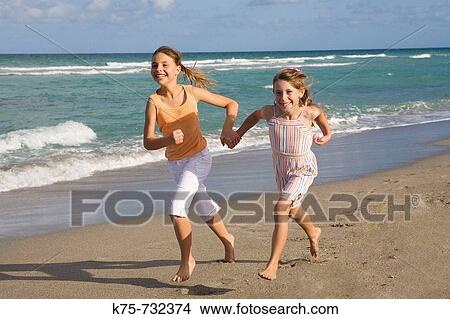 two happy young girls running together at beach View Large Photo Image Picture - two happy young girls running together at beach. Fotosearch