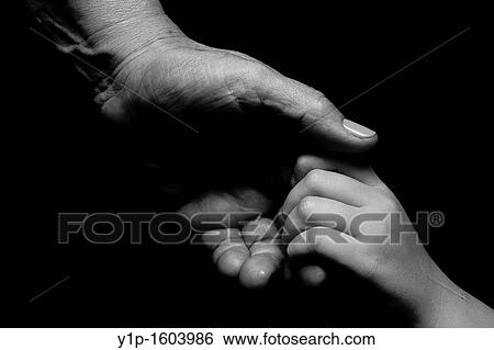 Stock Photograph - Two human hands adult and child on black background. Fotosearch