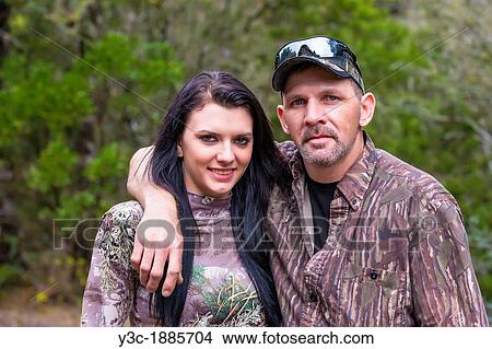Picture - Two hunters portrait, father and daughter in camouflage outfit, male Caucausian, 40 years old, female Caucasian with long black hair, 18 years old, Texas, USA. Fotosearch
