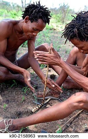 Two Jo/? hoansi San men sitting on the ground of the African savannah and making fire, Tsumkwe, Otjozondjupa Region, Namibia, Africa. View Large Photo Image Stock Image - Two Jo/? hoansi San men sitting on the ground of the African savannah and making fire, Tsumkwe, Otjozondjupa Region, Namibia, Africa.. Fotosearch