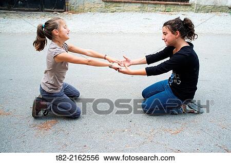 Two joyful girls playing, nine years old, holding hands, facing each other View Large Photo Image Stock Photograph - Two joyful girls playing, nine years old, holding hands, facing each other. Fotosearch