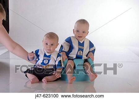 Two little boys aged 1 and 3 sitting in chairs wearing football shirts View Large Photo Image Stock Image - Two little boys aged 1 and 3 sitting in chairs wearing football shirts. Fotosearch