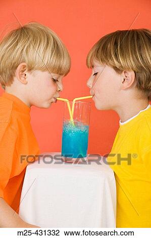 Two little boys drinking blue lemonade through straws out of the same glass sharing View Large Photo Image Stock Image - Two little boys drinking blue lemonade through straws out of the same glass sharing. Fotosearch