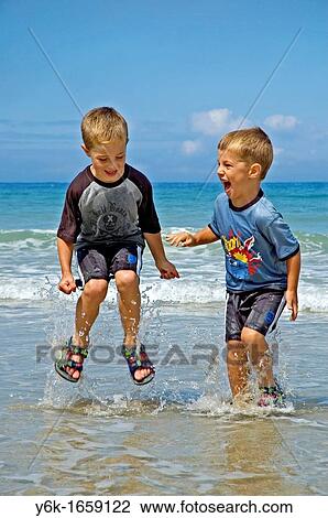 Stock Image - two little boys splashing in the sea in cornwall, uk. Fotosearch
