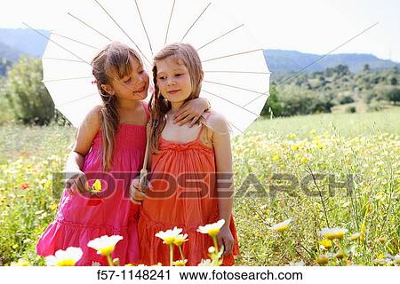 Two little girls in meadow View Large Photo Image Stock Image - Two little girls in meadow. Fotosearch