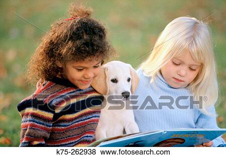 Two little girls reading with a puppy View Large Photo Image Stock Photo - Two little girls reading with a puppy. Fotosearch