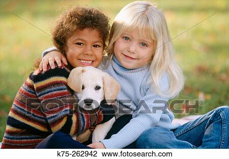 Stock Image - Two little girls with a puppy. Fotosearch