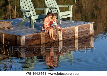 Two little sisters sitting on dock with feet in water View Large Photo Image Stock Image - Two little sisters sitting on dock with feet in water. Fotosearch