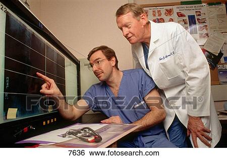 Stock Photograph - Two medical doctors exam x-rays on a light box in a hospital in Washington D. C.. Fotosearch