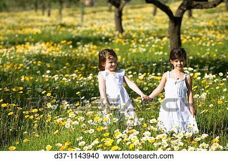 Two mediterranean girls in a yellow flower field View Large Photo Image Stock Image - Two mediterranean girls in a yellow flower field. Fotosearch