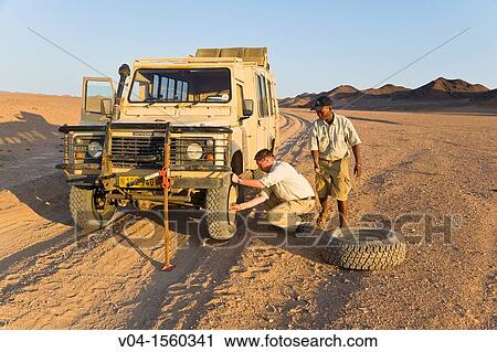 Two men changing a flat tyre in the desert, Namibia, Africa View Large Photo Image Stock Image - Two men changing a flat tyre in the desert, Namibia, Africa. Fotosearch