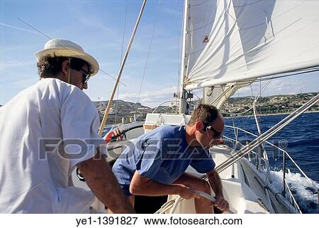 Two men navigating a sailboat off the coast of L? Estaque, Marseille, France View Large Photo Image Stock Photo - Two men navigating a sailboat off the coast of L? Estaque, Marseille, France. Fotosearch