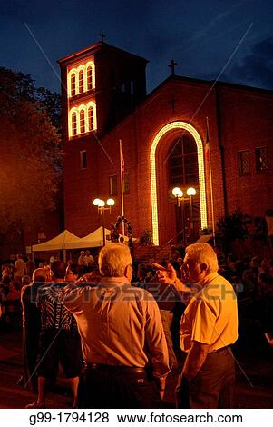 Stock Photo - Two men talk in the late evening during St Angela Merici Church 25th Anniversary celebration weekend. The church is in the heart of Little Italy. Windsor, Ontario, Canada.. Fotosearch