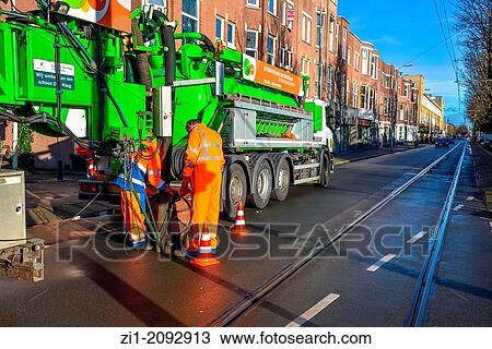 Stock Image - two men with sewage pumpmachine in big city in the Hague, Netherlands. Fotosearch