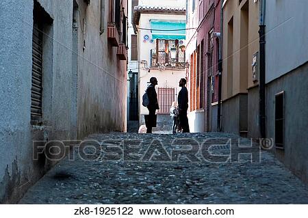 Stock Image - Two Moroccans speaking at the end of street in the Albaic? n Granada Spain. Fotosearch