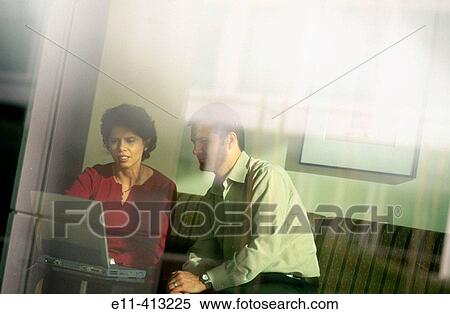 Two office workers work with a laptop computer View Large Photo Image Stock Photography - Two office workers work with a laptop computer. Fotosearch