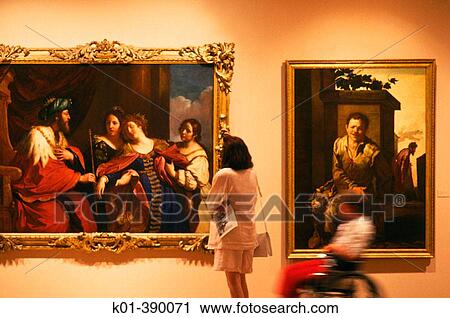 Stock Image - Two people at an art gallery one in a wheelchair.. Fotosearch