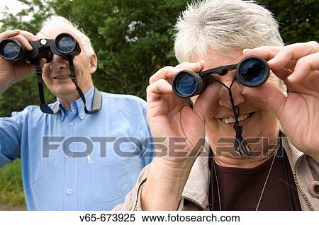 Two people, middle aged birdwatchers at Cors Caron nature reserve Tregaron, Ceredigion mid wales, looking through binoculars at the wild birds nesting in the wetlands View Large Photo Image Stock Photography - Two people, middle aged birdwatchers at Cors Caron nature reserve Tregaron, Ceredigion mid wales, looking through binoculars at the wild birds nesting in the wetlands. Fotosearch