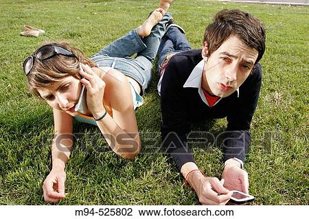 Two people on grass using palm pilot and cell phone View Large Photo Image Stock Image - Two people on grass using palm pilot and cell phone. Fotosearch