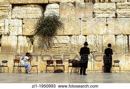 Stock Image - Two praying jews at the Wall at Jerusalem being photographed. Fotosearch