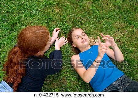 Two preteen girls lying on the grass, talking to each other View Large Photo Image Stock Photography - Two preteen girls lying on the grass, talking to each other. Fotosearch