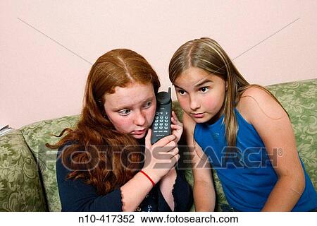Two preteen girls sitting on a sofa, talking on the telephone. View Large Photo Image Stock Image - Two preteen girls sitting on a sofa, talking on the telephone.. Fotosearch