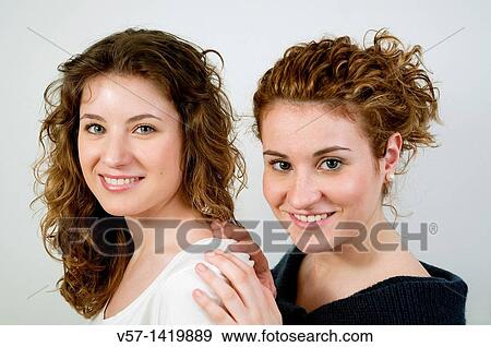 Stock Photo - Two pretty young women smiling and looking at the camera. Fotosearch