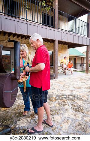 Stock Photo - Two retired couples at a backyard babecue party. Caucasians, Males and females in the 60s.. Fotosearch