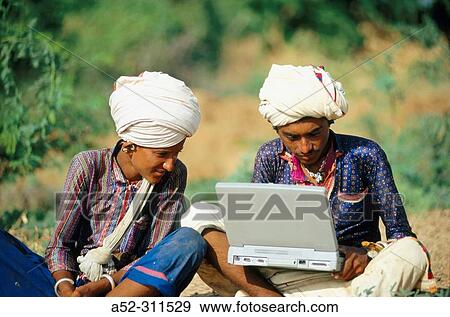 Two rural Indians with white turbans working on a laptop in Kutch, Gujarat, India. View Large Photo Image Stock Photo - Two rural Indians with white turbans working on a laptop in Kutch, Gujarat, India.. Fotosearch