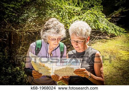two senior women hikers look at a map in a forest on Saturna Island, BC, Canada View Large Photo Image Picture - two senior women hikers look at a map in a forest on Saturna Island, BC, Canada. Fotosearch