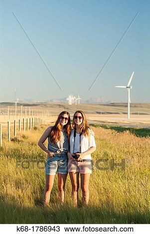 Stock Image - Two sisters, 16 and 20, stand in a field in southern Alberta, Canada. Fotosearch