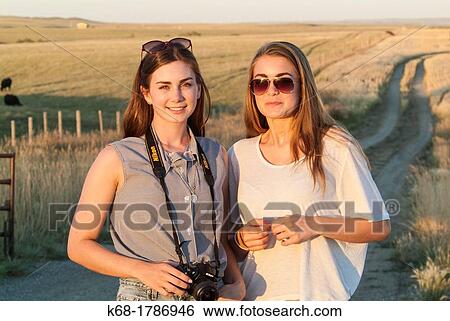 Stock Photograph - Two sisters, 16 and 20, stand on a road in southern Alberta, Canada. Fotosearch