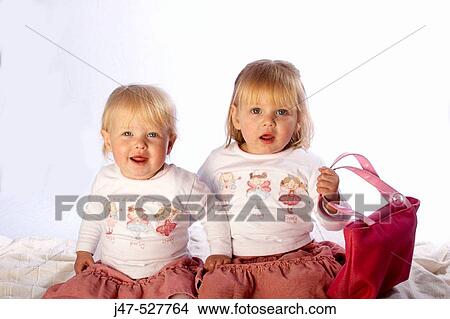 Two sisters, 2 and 3, sitting together, smiling into camera View Large Photo Image Picture - Two sisters, 2 and 3, sitting together, smiling into camera. Fotosearch