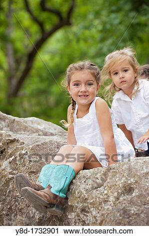 Two sisters, four and five years old are playing outdoors on a rock View Large Photo Image Stock Image - Two sisters, four and five years old are playing outdoors on a rock. Fotosearch