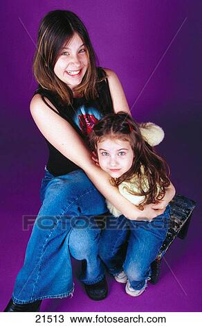 Two sisters hugging and looking up at camera View Large Photo Image Stock Image - Two sisters hugging and looking up at camera. Fotosearch